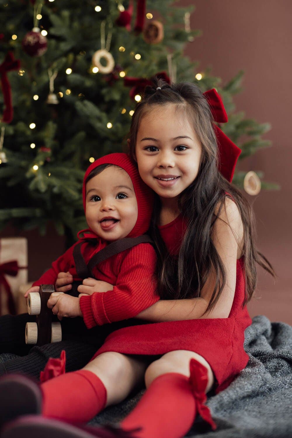 Deux sœurs souriantes devant un sapin de Noël, mini séance photo de Noël à Strasbourg