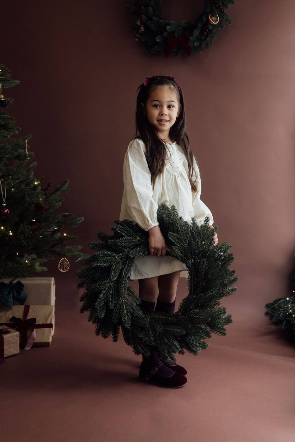 Fillette en robe blanche qui tient une couronne de Noël, studio photo à Strasbourg-Neudorf