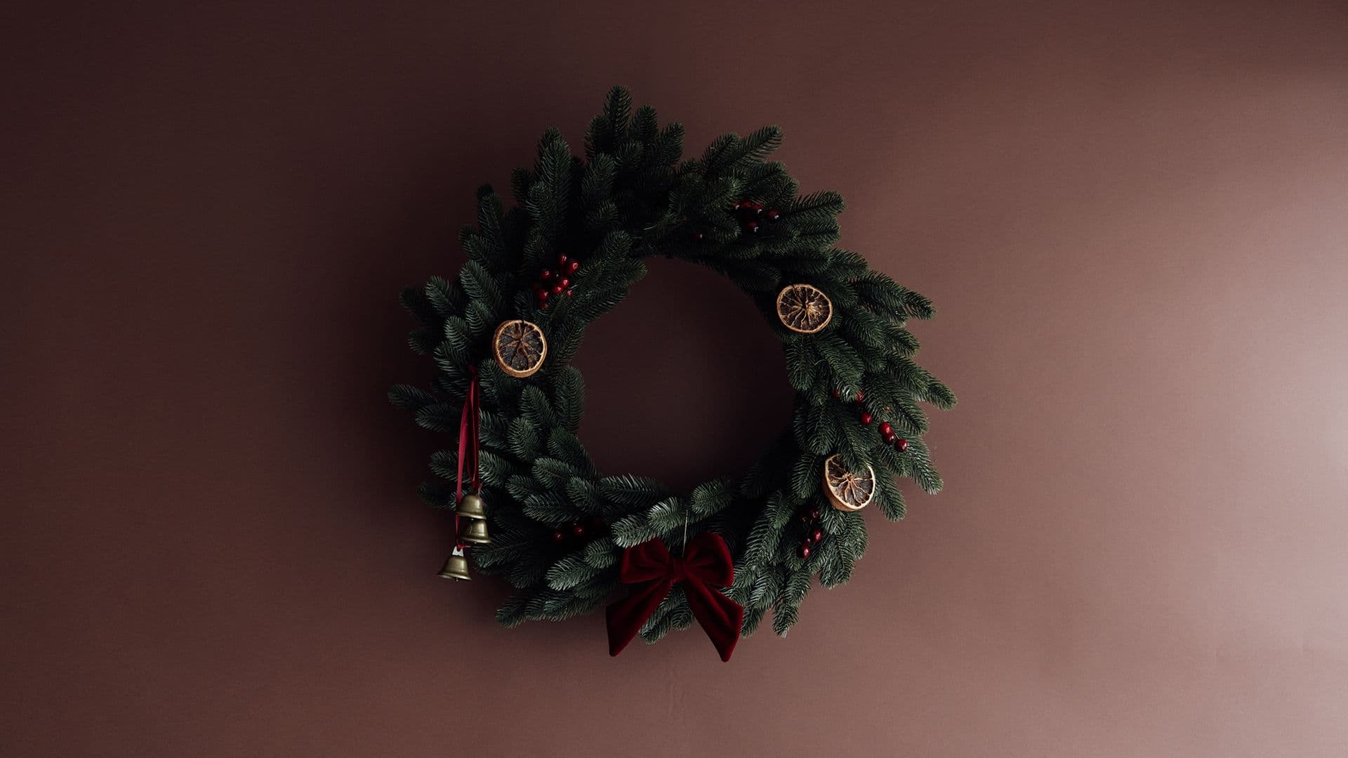 Couronne de Noël avec oranges séchées et nœud en velours rouge sur fond brun, séance photo de Noël à Strasbourg